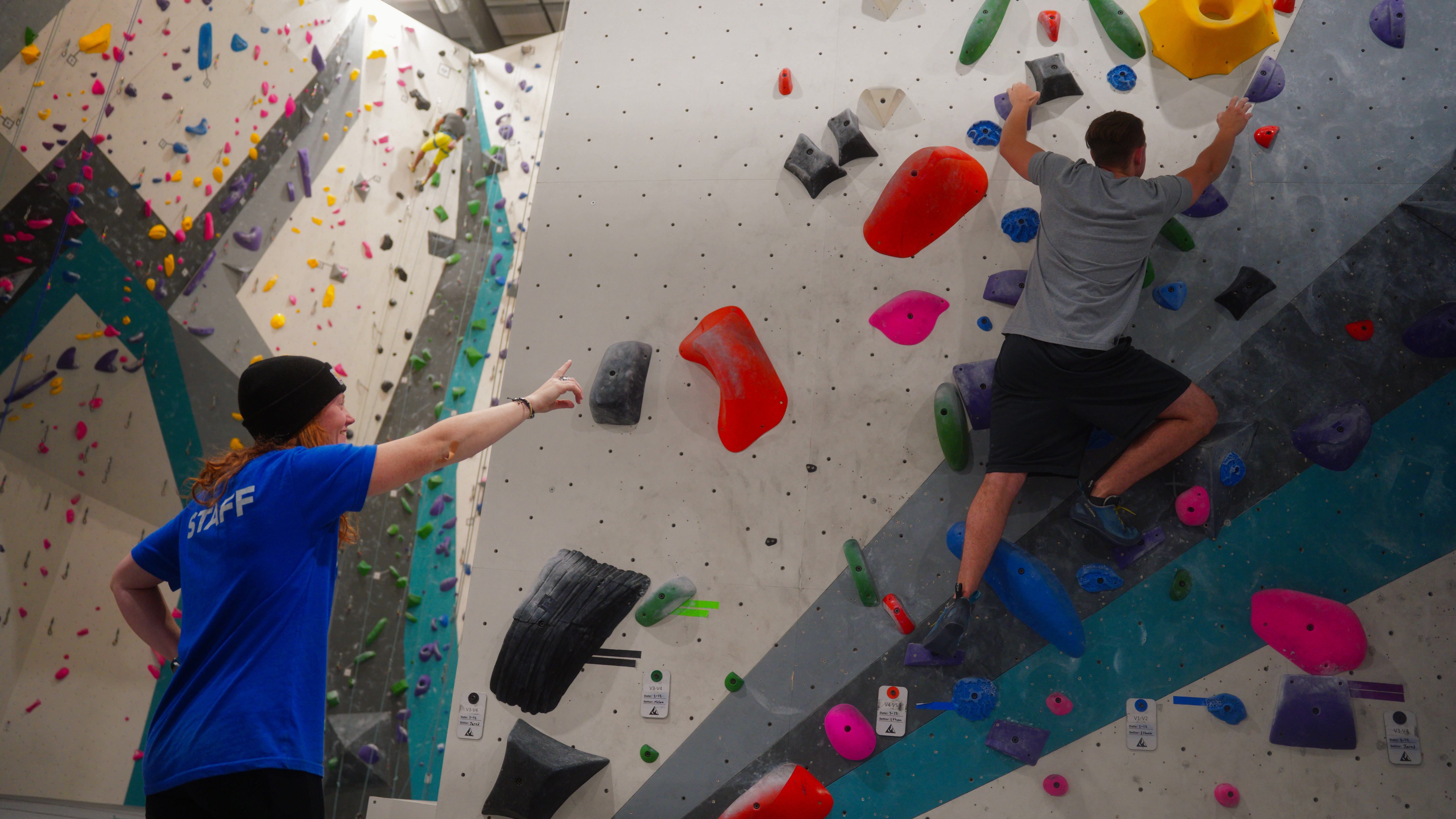 Alpine staff guiding a beginner climber on the bouldering wall